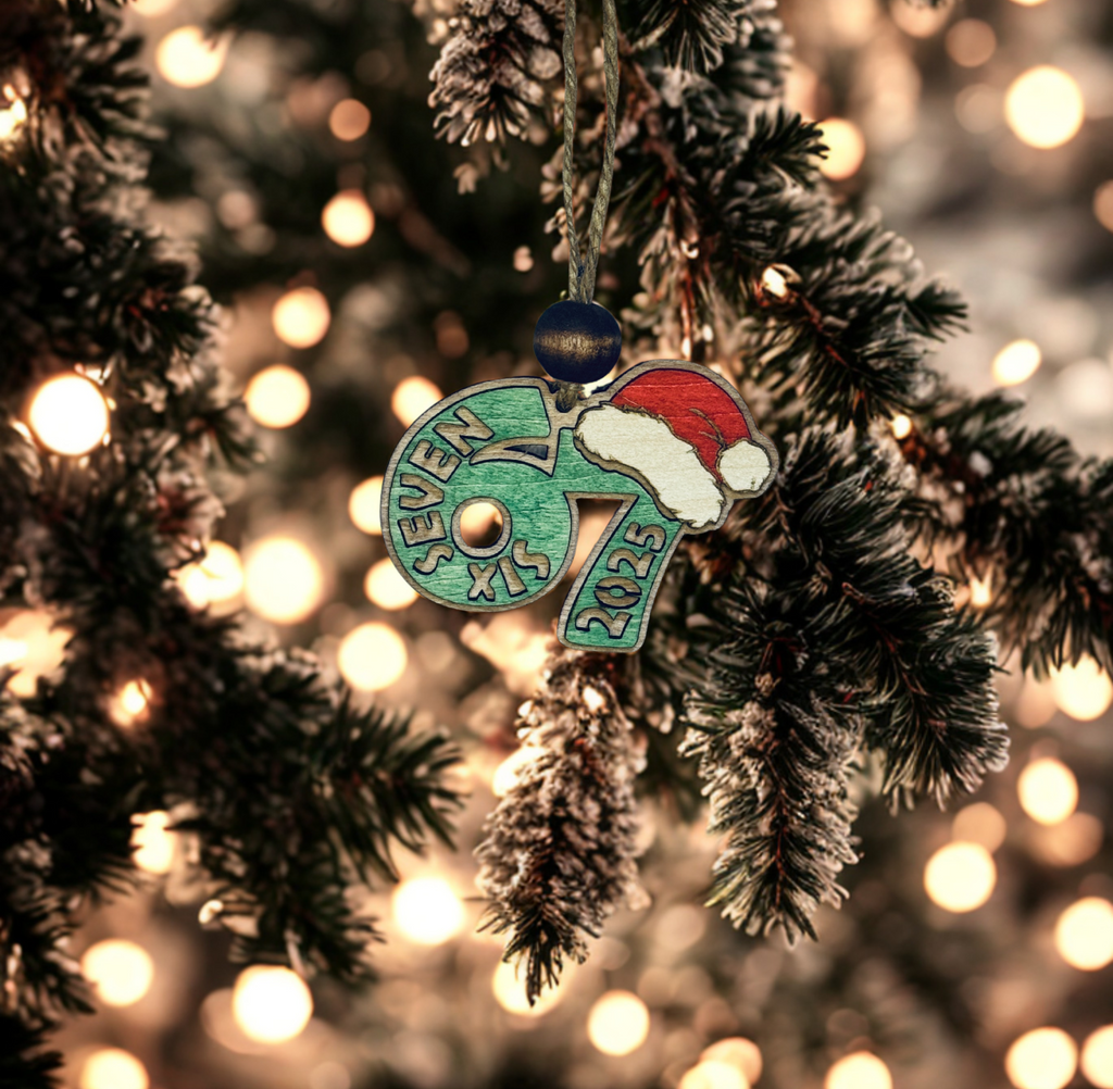 Decorative green ornament with 67 Six Seven 2025 on a Christmas tree with lights.