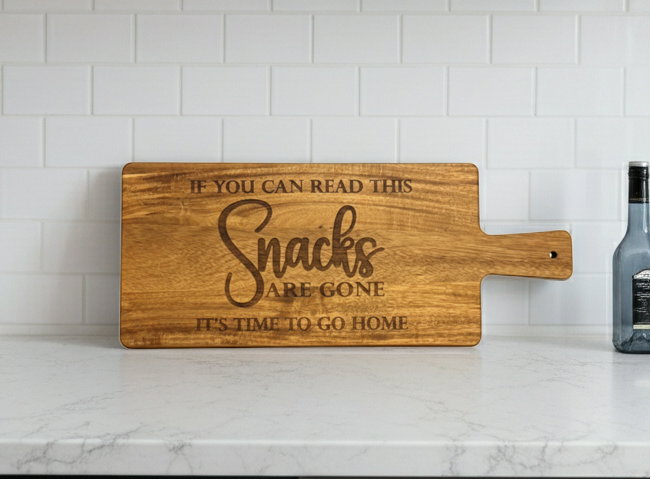 Wooden cutting  charcuterie board with humorous  Snacks are gone it's time to go home text on a kitchen counter.