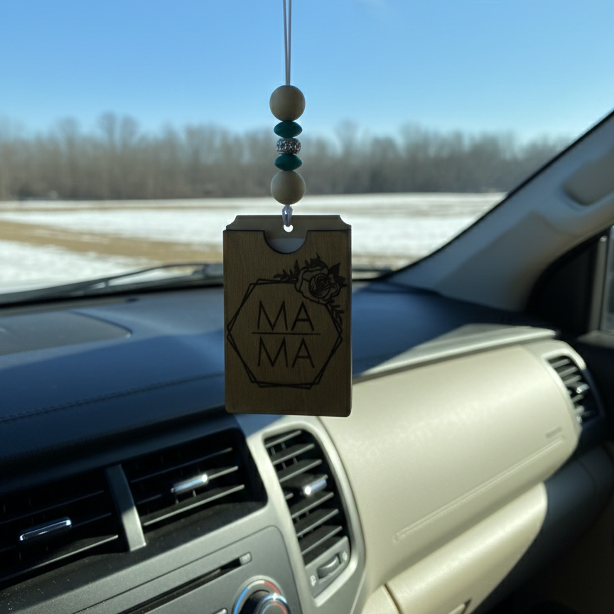 Wooden car freshener with engraved mama inside a floral frame hanging from a rearview mirror