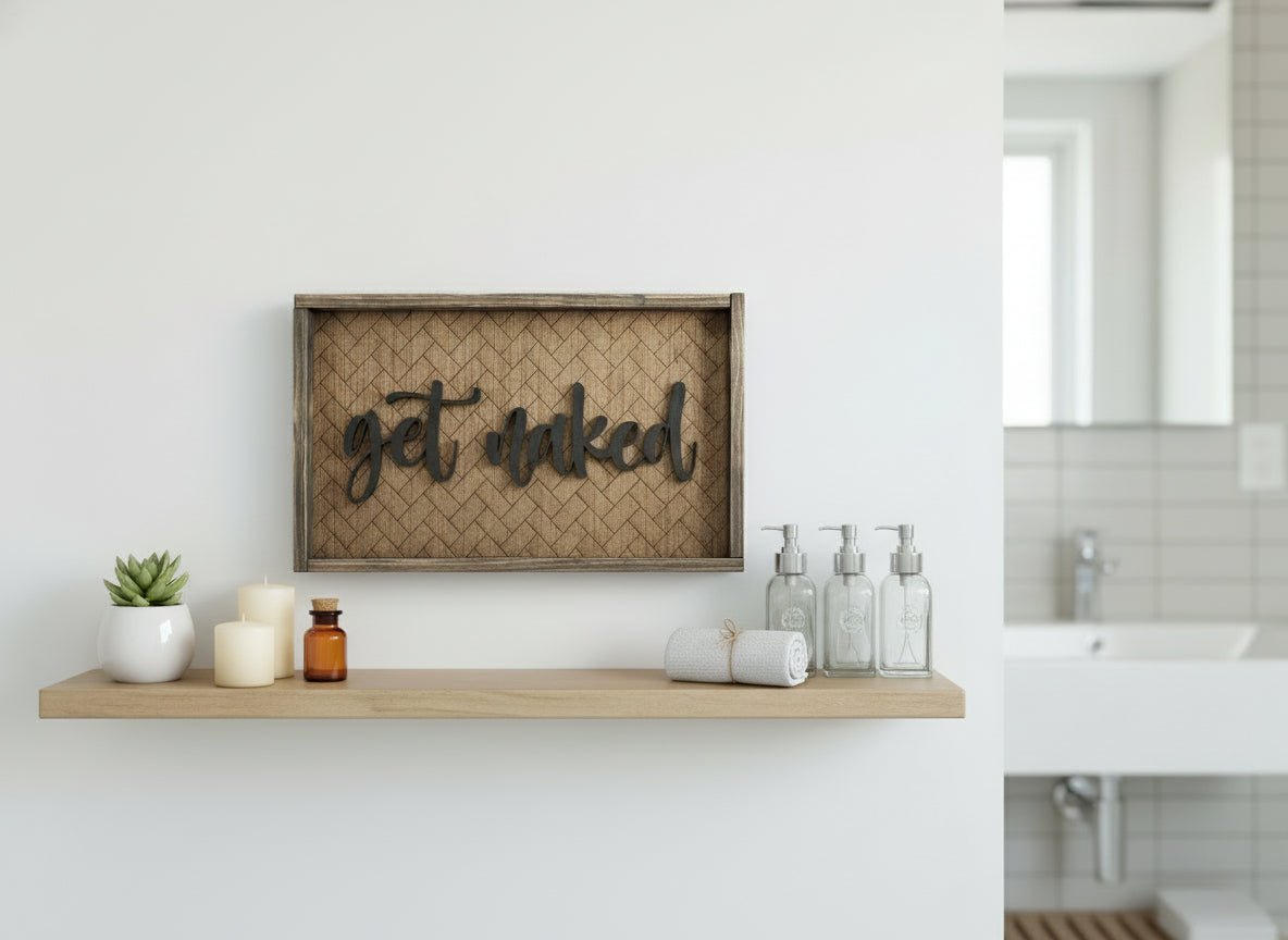 Wooden framed sign with laser engraved herringbone pattern and laser cut get naked hanging on a wall in a bathroom 