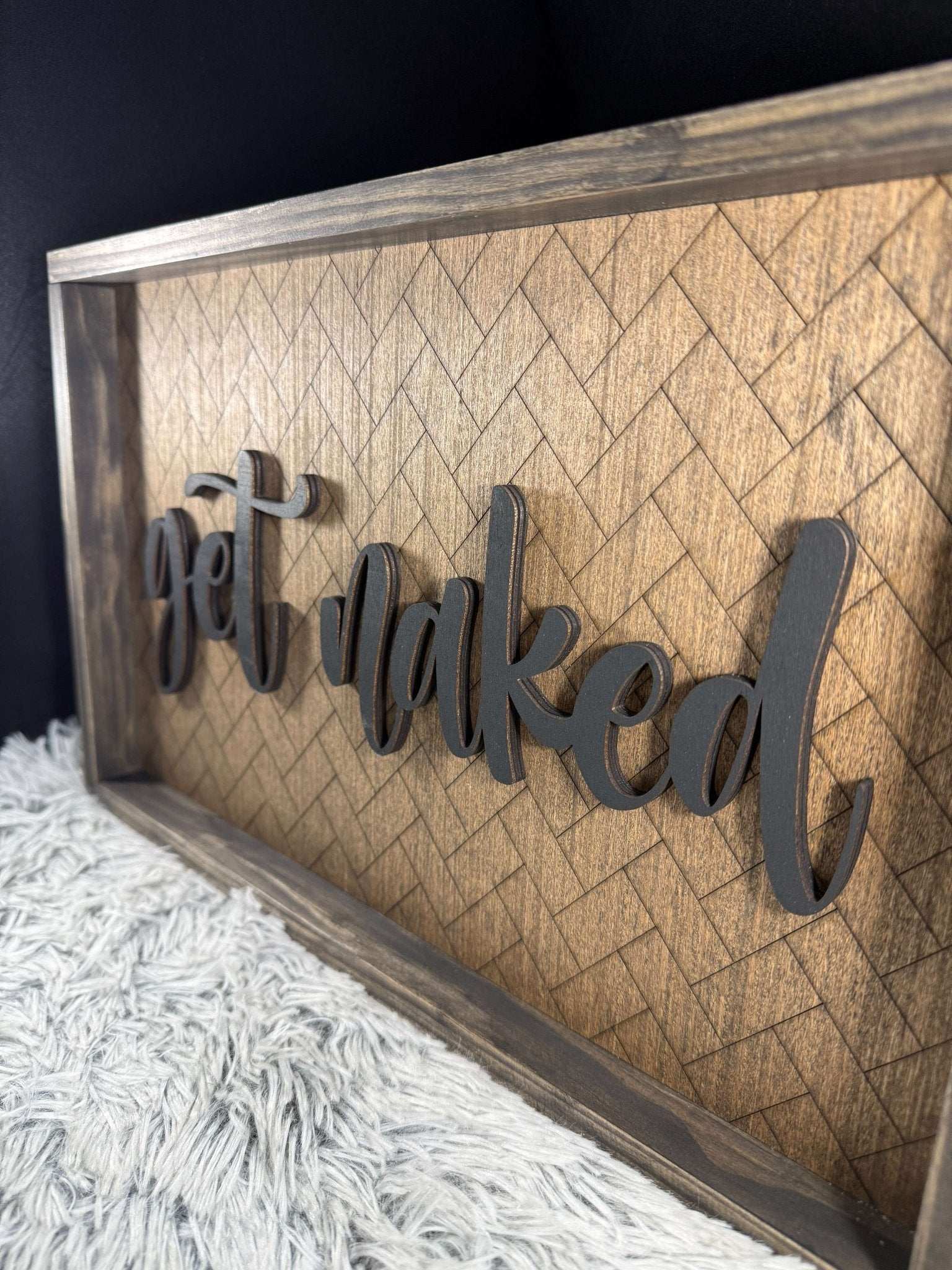 Wooden framed sign with laser engraved herringbone pattern and laser cut and painted get naked 