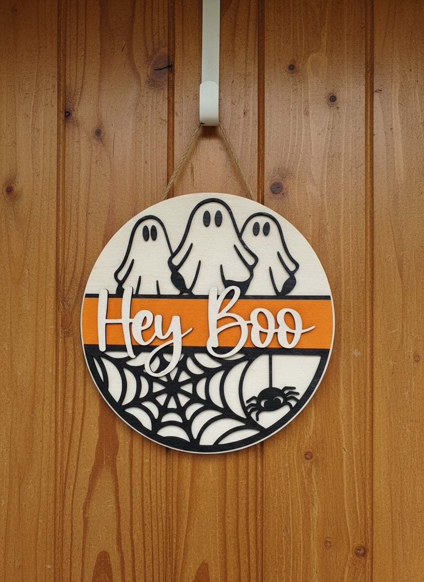 Decorative Halloween-themed wall art with a spider and ghosts and 'Hey Boo' text on a white background.
