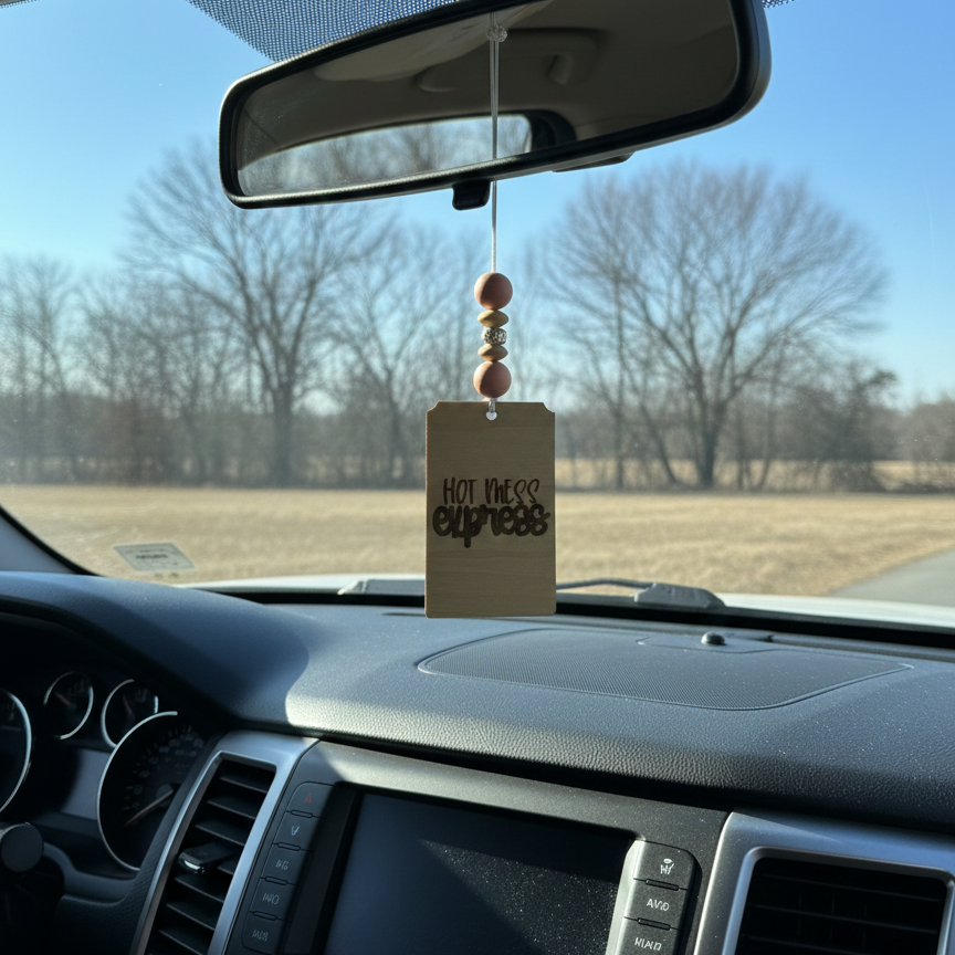 Wooden car freshener that says hot mess express with light pink beads hanging from a rearview mirror