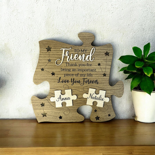 Wooden puzzle piece to my friend thank you for being an important piece of my life love you forever with engraved message and names on a wooden surface with a plant in the background.