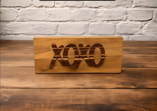 wood sign with the word xoxo sitting on a wood table with a brick backgroung